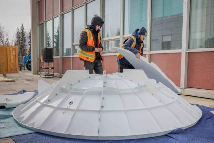 University of Alaska Fairbanks Facilities Services employees Mckinley Hearns, left, and Shae Patterson assemble the reflector dish of the new Geographic Information Network of Alaska antenna on Wednesday, April 3, 2024. Photo by Bryan Whitten