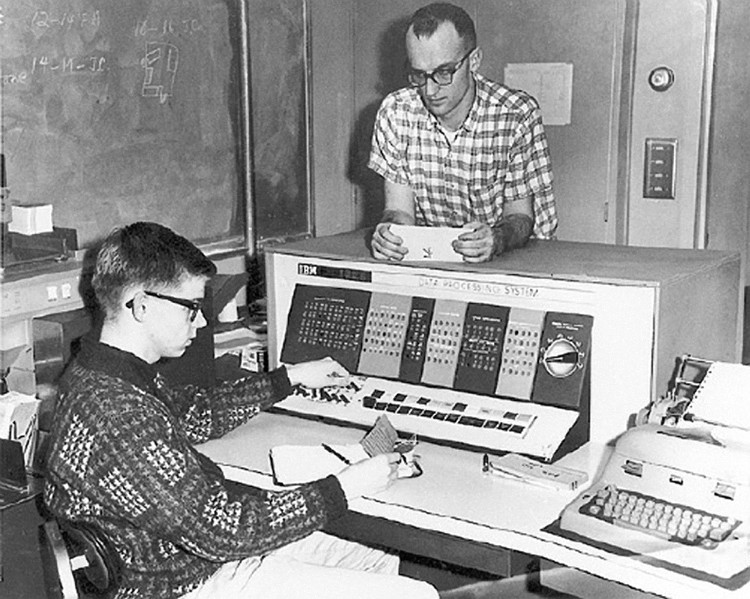 IBM 1620 Computer with two people: one using, one watching