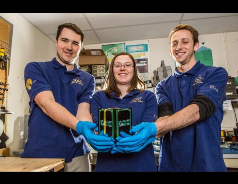 Engineering majors (L to R) Jesse Frey, Morgan Johnson, and Patrick Wade hold the cubesat they designed and built as part of their work with the Alaska Space Grant program. The miniature satellite is scheduled to be launched into space Oct. 8, 2015, from Vandenberg AFB, CA. UAF photo by Todd Paris.