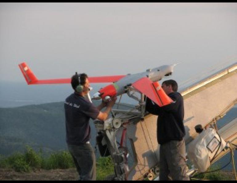 Martin Susser, left, program manager at Insitu, Inc., and the UAF Geophysical Institute’s Don Hampton load a 40-pound unmanned aerial system onto its launcher at the Stewart Creek impact area in June 2007. Geophysical Institute photo by Kevin Engle.