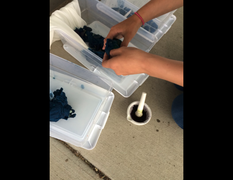 A  summer camp participant uses local flower pigments and natural indigo to create dye patterns on a silk scarf. Photo by Perrin Teal Sullivan