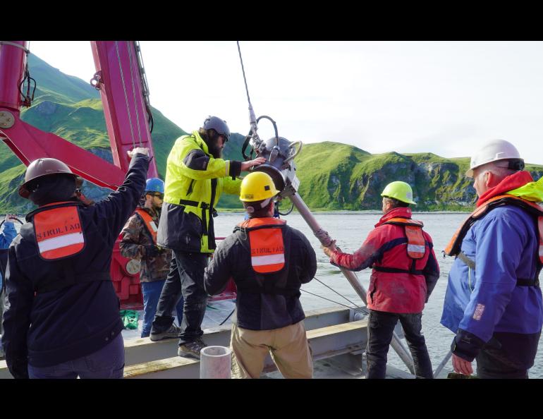 A team aboard the research vessel Sikuliaq handles an instrument during the 2022 cruise investigating the Aleutian Islands’ storm and tsunami history. Photo courtesy of Sarah Betcher/Farthest North Films