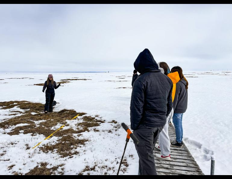 The Geophysical Institute's Serina Wesen discussing spring snow melt mechanisms with rural high school students attending Ilisaġvik College’s “Community Environmental Monitoring Camp” at Barrow Environmental Observatory in June 2024 in Utqiaġvik, Alaska. Photo by Howie Epstein