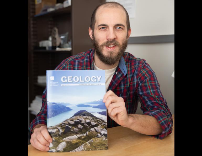 Associate professor Sean Regan holds a copy of the December edition of Geology, which features his latest research in its cover photo. Photo by Bryan Whitten