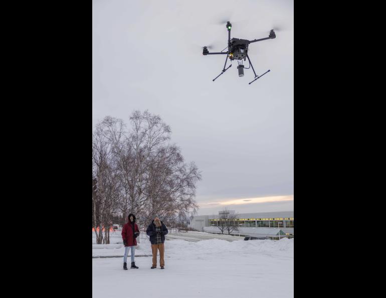 Chief pilot Jason Williams of the Alaska Center for Unmanned Aircraft Systems Integration, at right, controls a drone carrying the science instruments during a test flight Jan. 17, 2025. Research assistant professor Társilo Girona watches. Photo by Eric Marshall