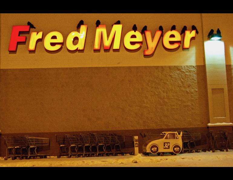 Ravens roost for the night on the letters of a grocery store in Fairbanks. Photo by Douglas Yates.