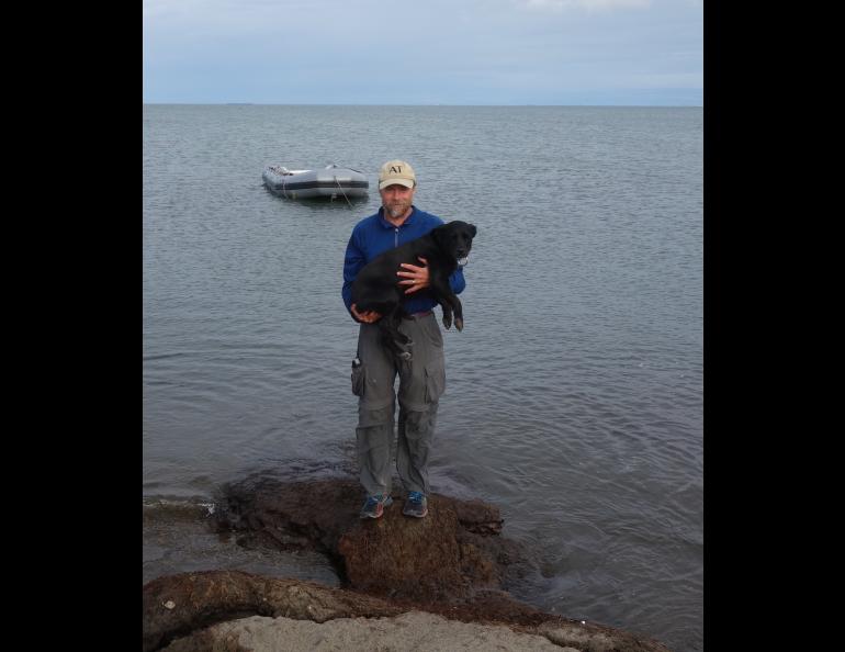 Ned Rozell and his dog Cora with the Arctic Ocean and Prudhoe Bay in the background on the day they finished their trans-Alaska hike. Photo by Becky Baird.