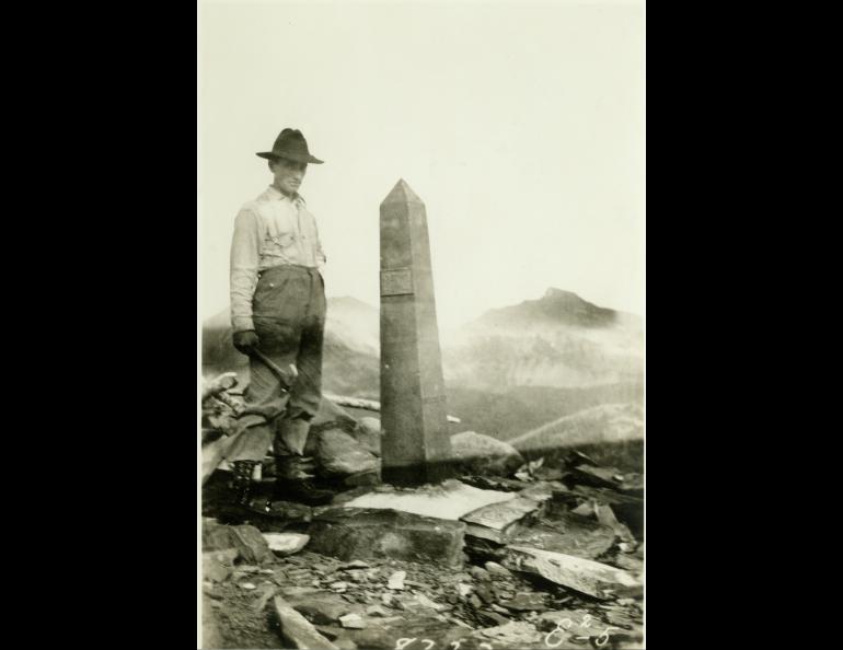 A man working with the International Boundary Commission in the early 1900s poses next to one of more than 200 obelisks that line the Alaska/Canada border. NOAA Photo Library.