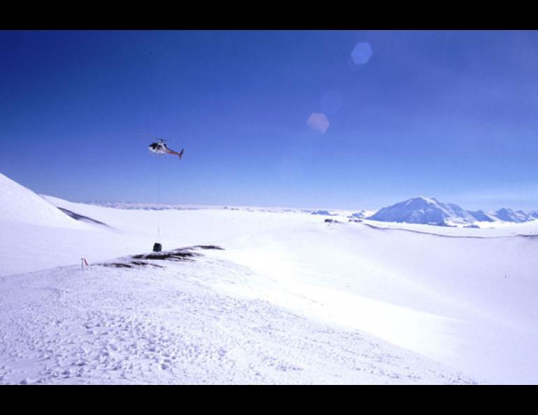  A helicopter pilot lowers a fiberglass hut onto Mount Wrangell in July 2000. Guy Tytgat, a volcano seismologist at the Geophysical Institute, was there at the 14,000-foot level on Wrangell to install seismometers within the hut. The Alaska Volcano Observatory now monitors the volcano with four such stations on its flanks. Guy Tytgat photo. 