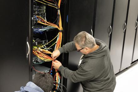 Kevin Galloway, left, and Mike Steinhauer of the Geophysical Institute’s Research Computing Systems unit attach cabling in August 2024 for the final and largest GPU node to be installed. Photo by LJ Evans