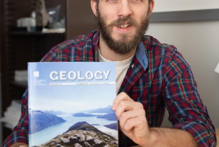 Associate professor Sean Regan holds a copy of the December edition of Geology, which features his latest research in its cover photo. Photo by Bryan Whitten