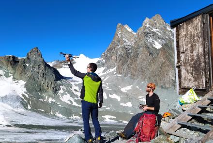Pascal Buri, left, holds a drone ready for flying in the Swiss Alps in August 2021 for the study of how mountain glaciers interact with the atmosphere. Thomas Shaw of the Institute of Science and Technology Austria prepares to pilot the drone. Photo courtesy of Pascal Buri